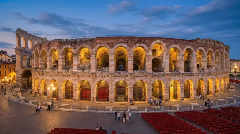 Arena di Verona illuminata al tramonto con archi in pietra e alcune persone in piazza