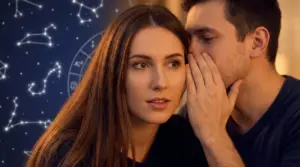 Un uomo sussurra all’orecchio di una donna davanti a simboli e costellazioni dello zodiaco sullo sfondo