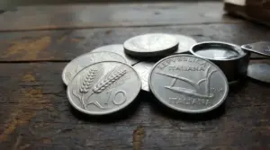 Monete italiane da 10 lire con la spiga su tavolo in legno, con lente d’ingrandimento per valutazione numismatica
